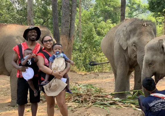 My husband and I holding our twin 1 year old boys in front of 2 elephants in Chiang Mai, Thailand