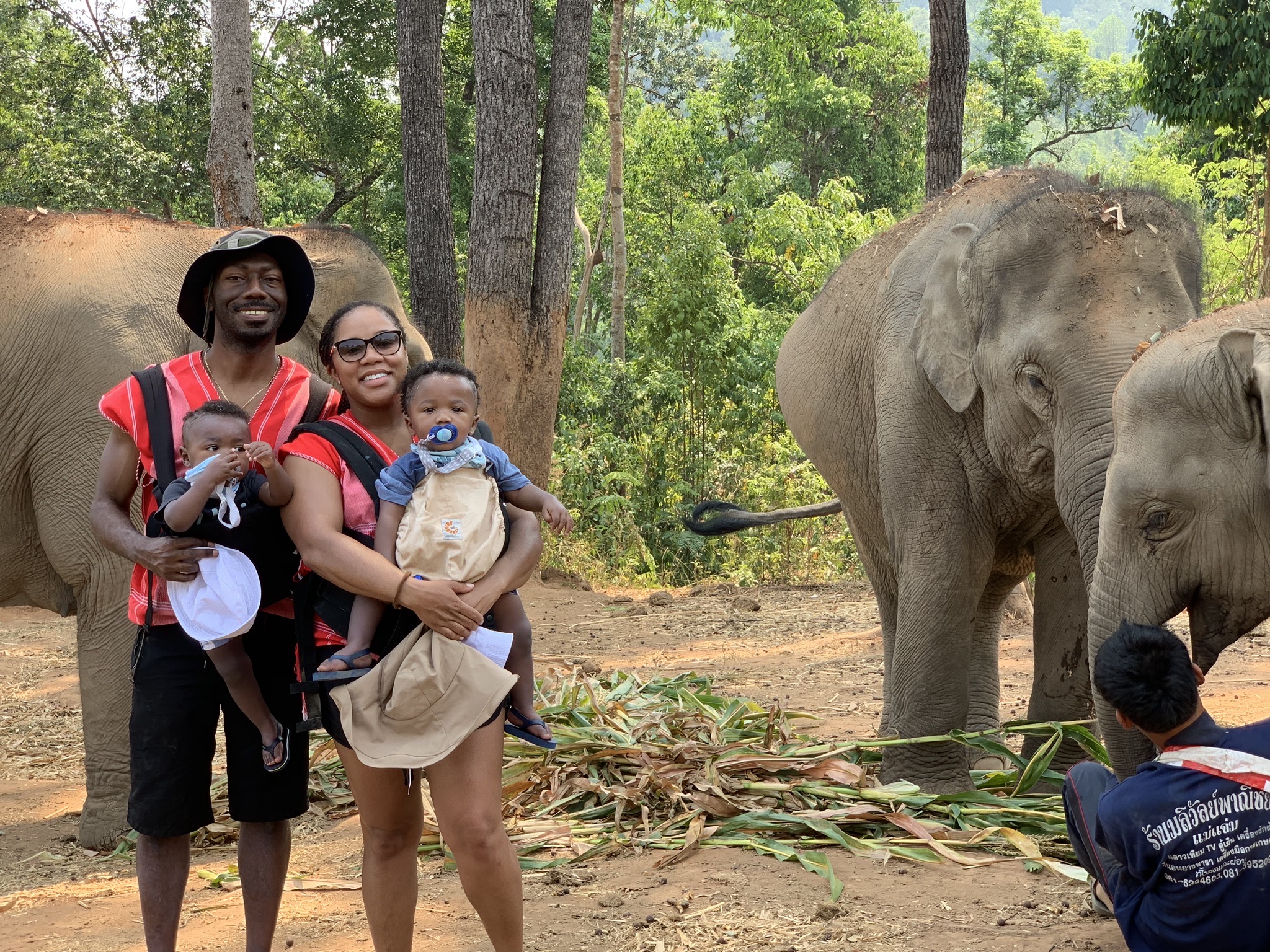 My husband and I holding our twin 1 year old boys in front of 2 elephants in Chiang Mai, Thailand