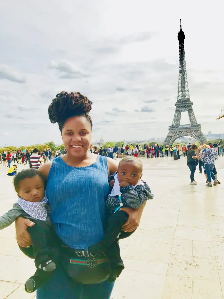 Mom holding twin 6 month boys in front of the Eiffel tower in Paris