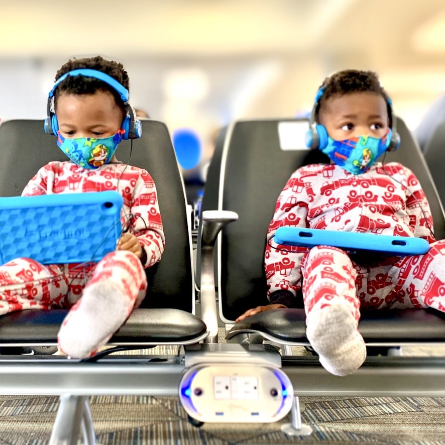 My twin boys distracted by their tablets and foldable headphones at the airport. Entertainment is a toddler travel essential!