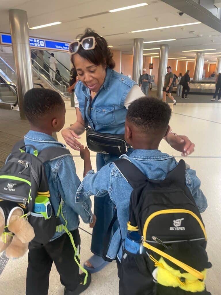 My twins greeting my mom at the airport with their travel backpacks in town