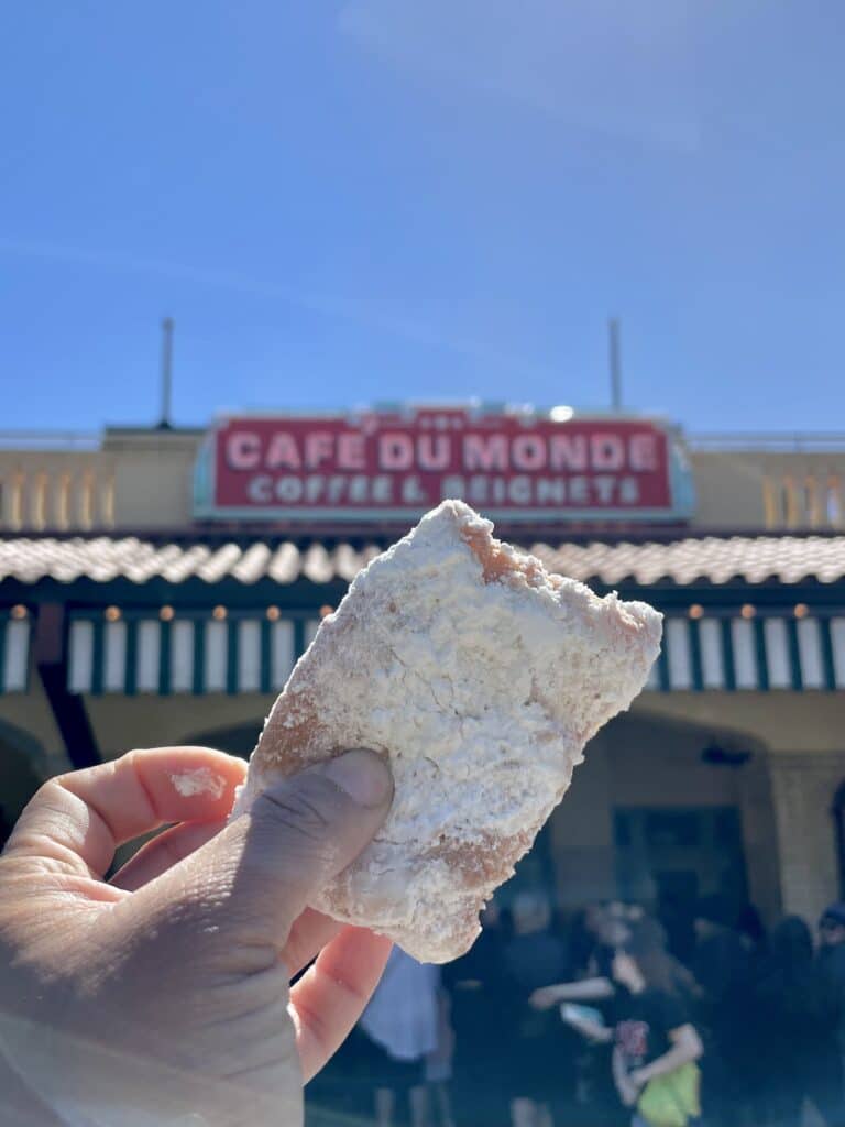 The infamous Cafe du Monde beignet being held in front of the restaurant- most definitely makes New Orleans worth visiting
