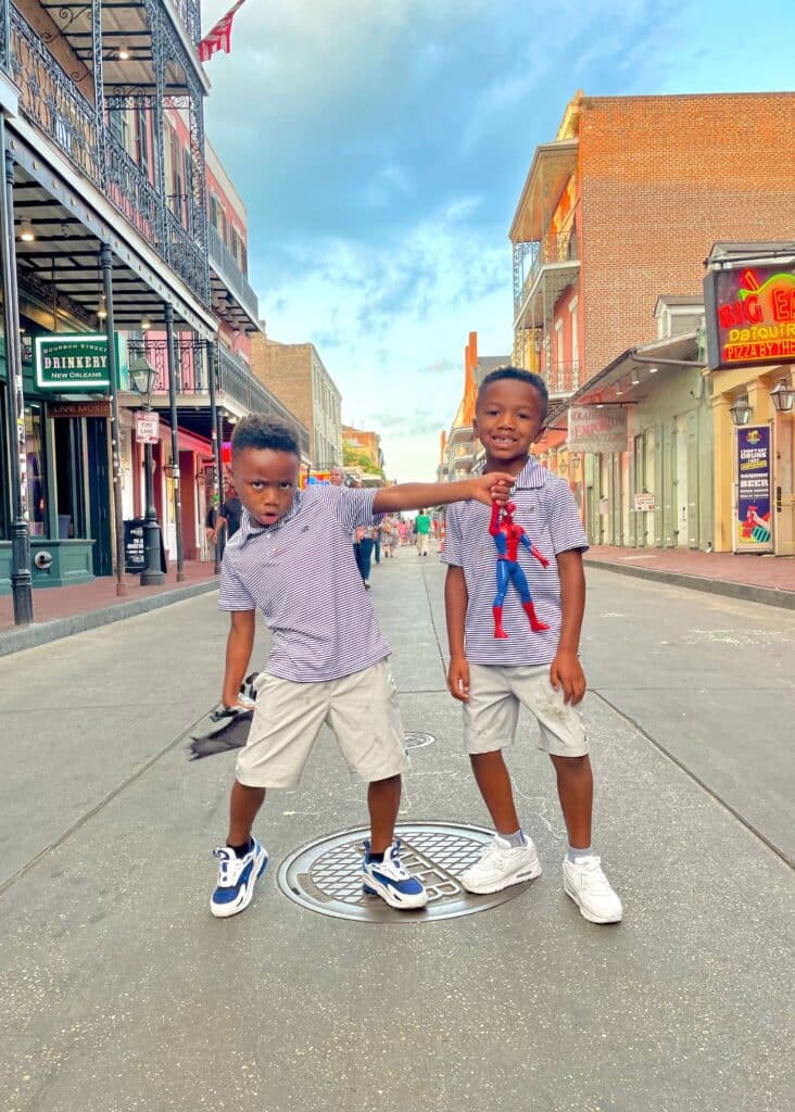 The twins in matching outfits posing on a New Orleans street. If you're wondering is New Orleans worth visiting for families – it is!