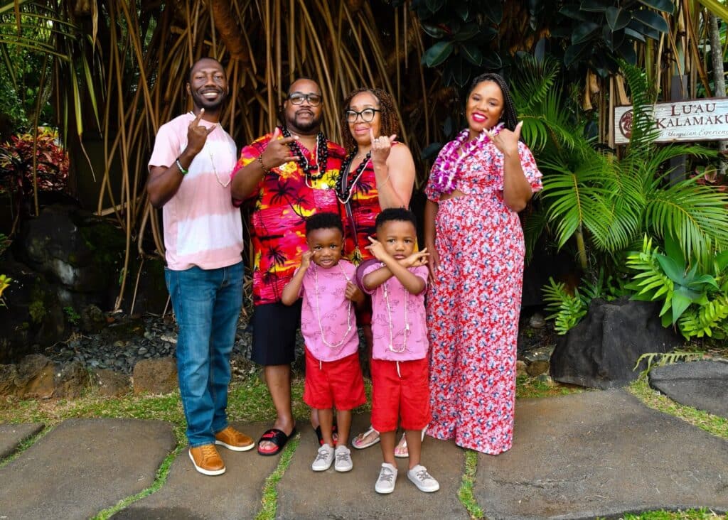 My family in Hawaii posing before our Luau. We're wearing a mix of pink and red co-ords, shorts, and Hawaiian shirts.