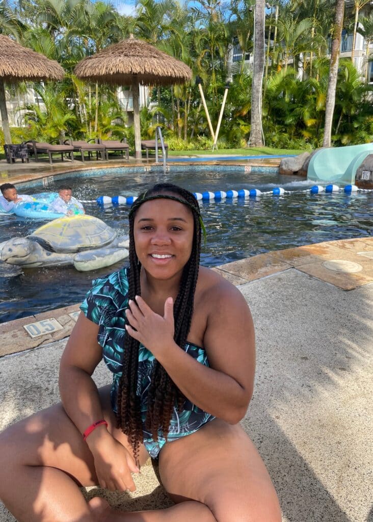 Me in a blue one piece swimsuit next to the pool in Hawaii.