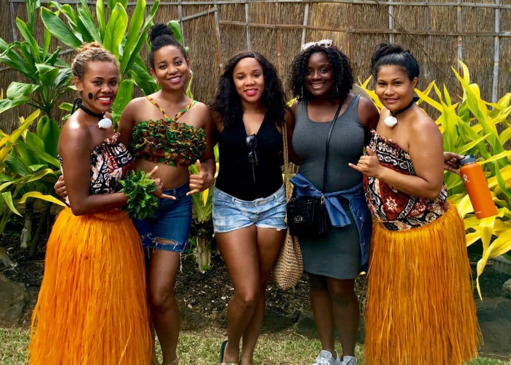 The girls and I posing with a couple of Hula dancers in orange grass skirts before a Luau.