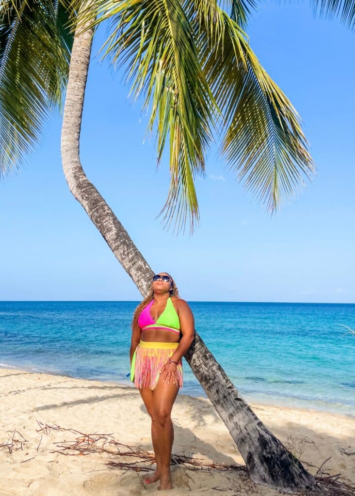 Me in a bikini and grass skirt cover up standing on the beach in Grenada.