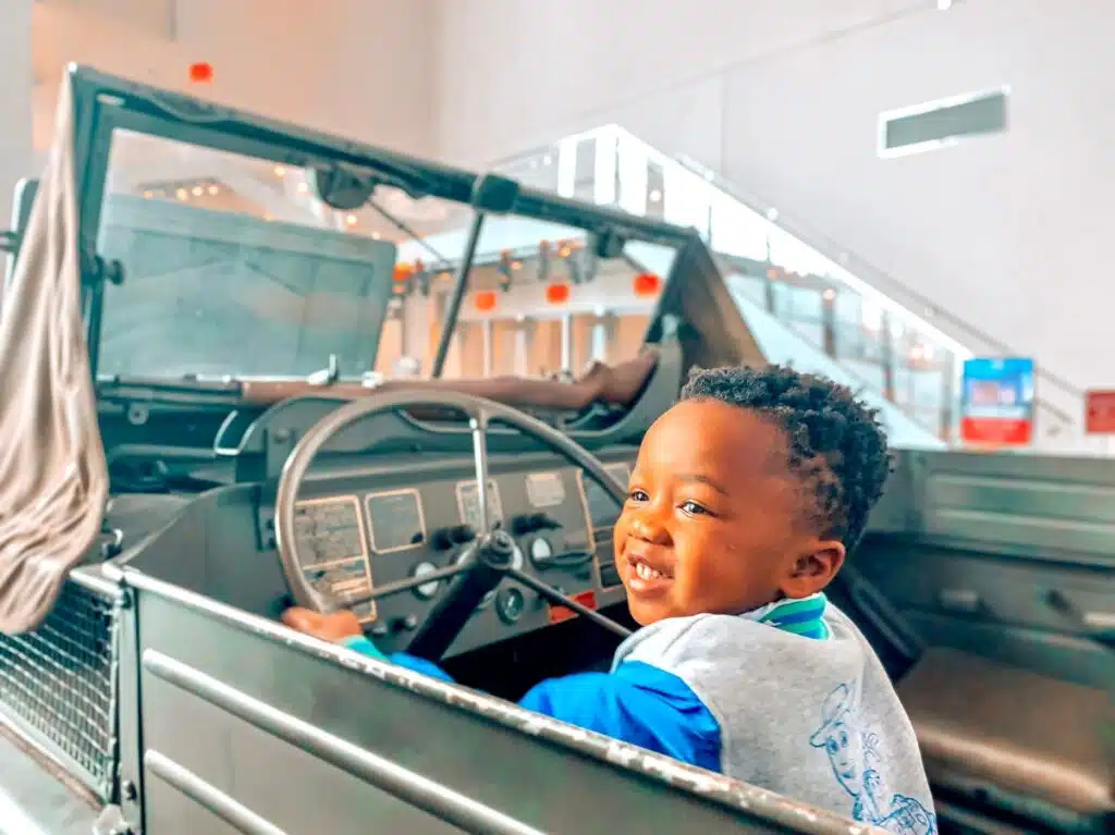 My son smiling in the driver's seat of an old WWII vehicle at the museum.
