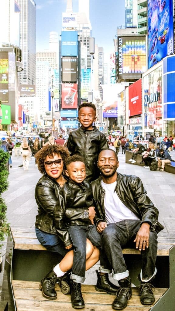Family of 4 with twin boys wearing black leather jackets and denim bottoms, in New York's Time Square