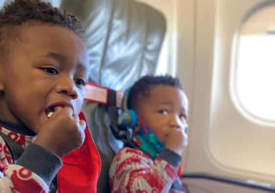 Twin boys sitting on a plane secured in their CARES Harness