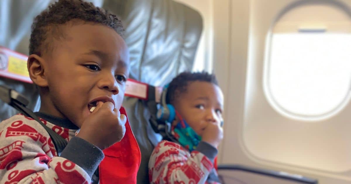 Twin boys sitting on a plane secured in their CARES Harness