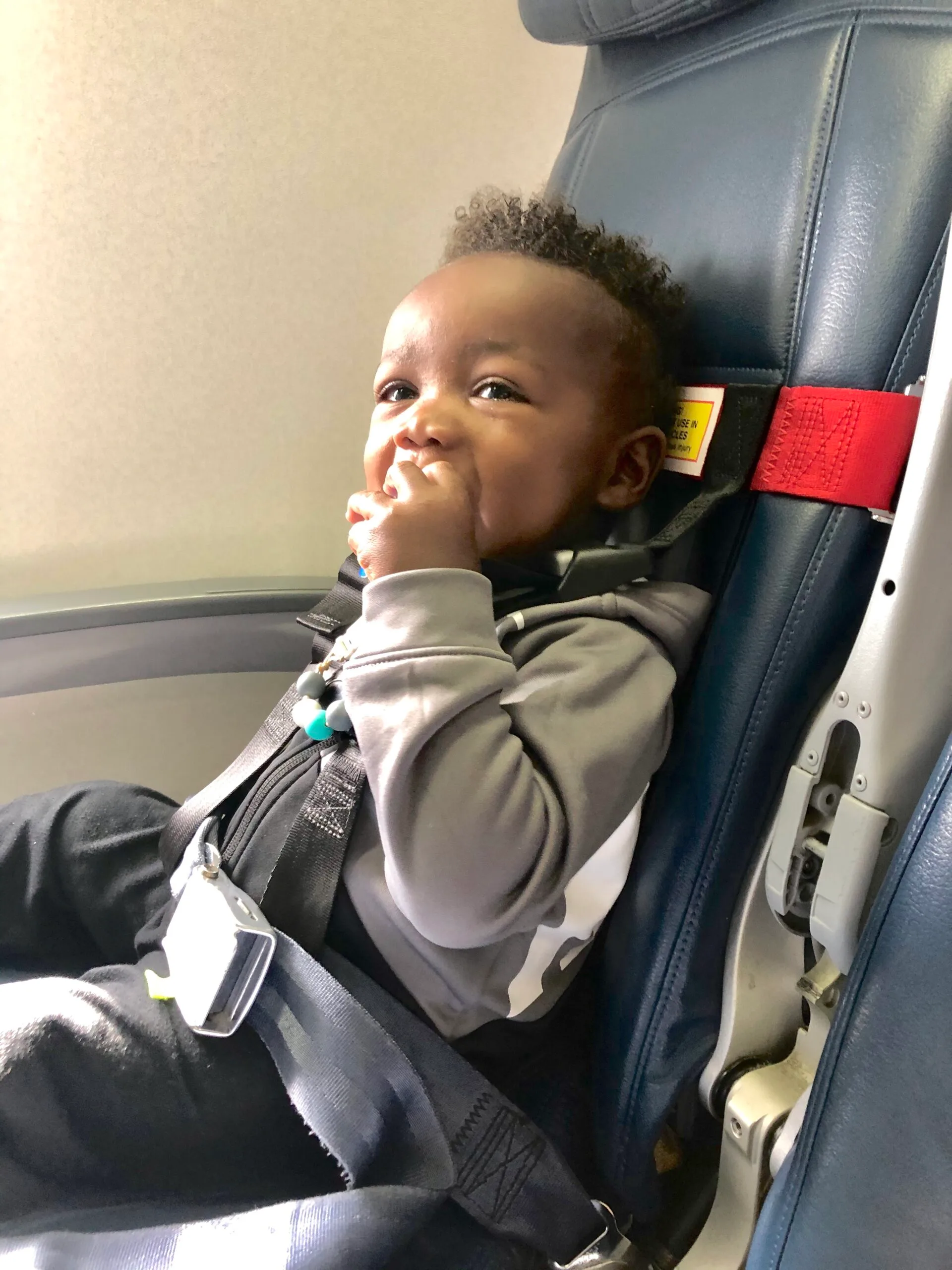 My son sitting on the plane in his CARES Harness while sucking on a pacifer 