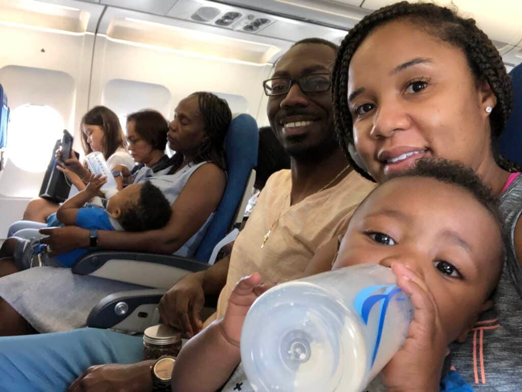 Family of 5 on a flight to Thailand. Mom and dad are sitting on one side of the aisle- holding one twin, while auntie is on the other side holding the other twin. Both twins are drinking a bottle