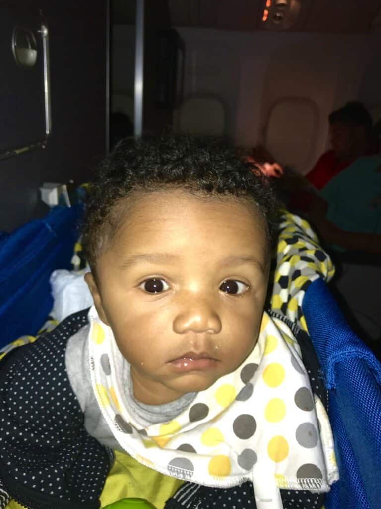 baby sitting in an airplane bassinet