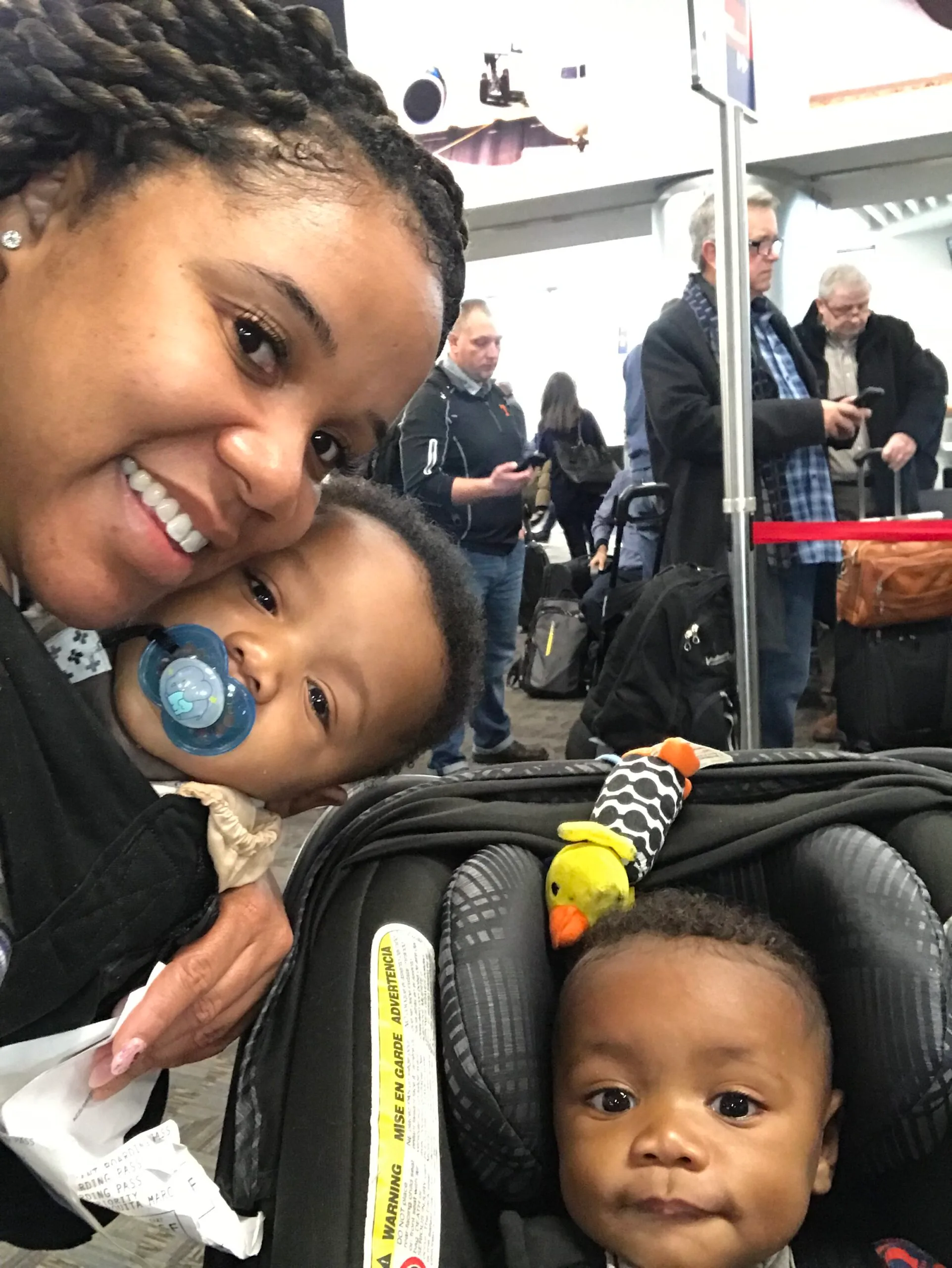 A twin mom baby wearing one baby, while the other baby is in the stroller