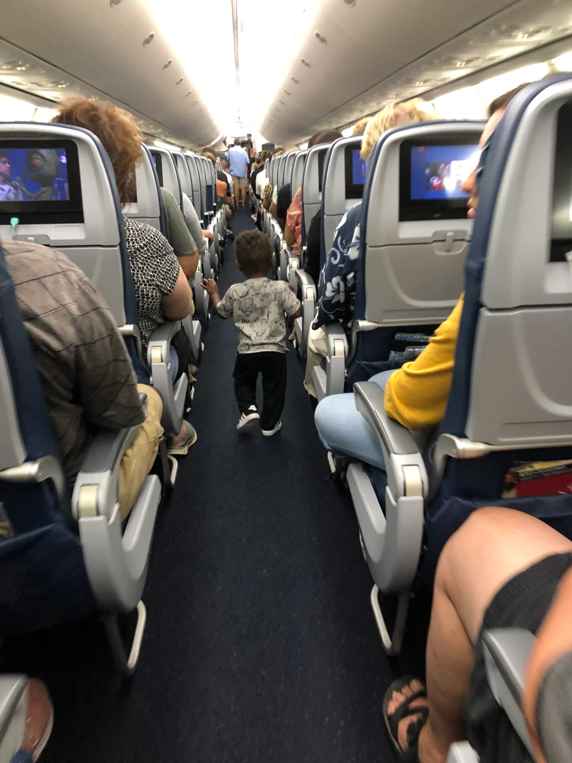 young toddler walking down the aisle of a plane