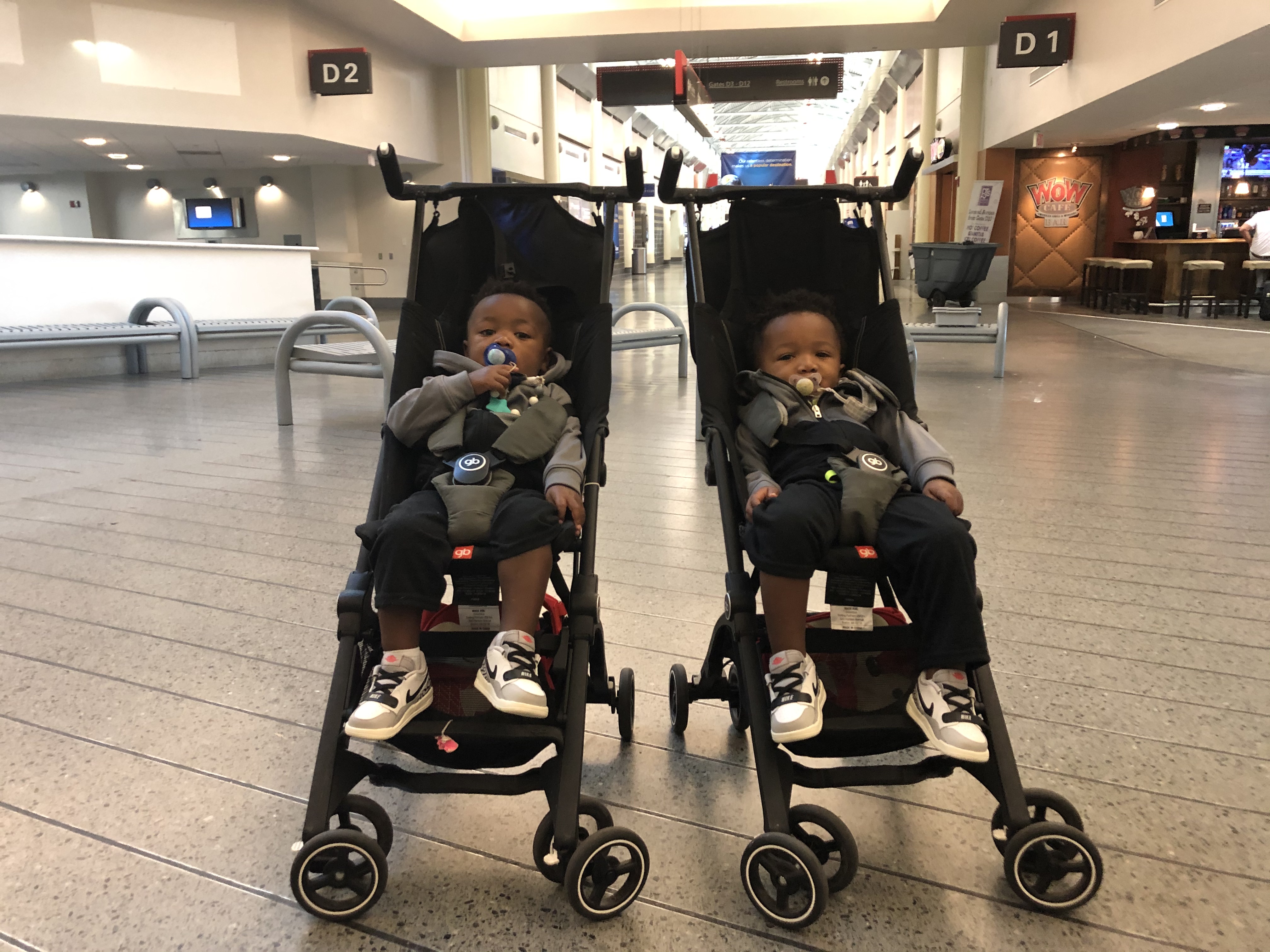 Twin toddlers sitting in their GB Pocket strollers right outside of airport security