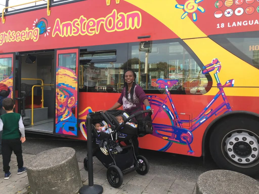 Twin boys in their double stroller with their aunt in front of the Amsterdam hop on hop off