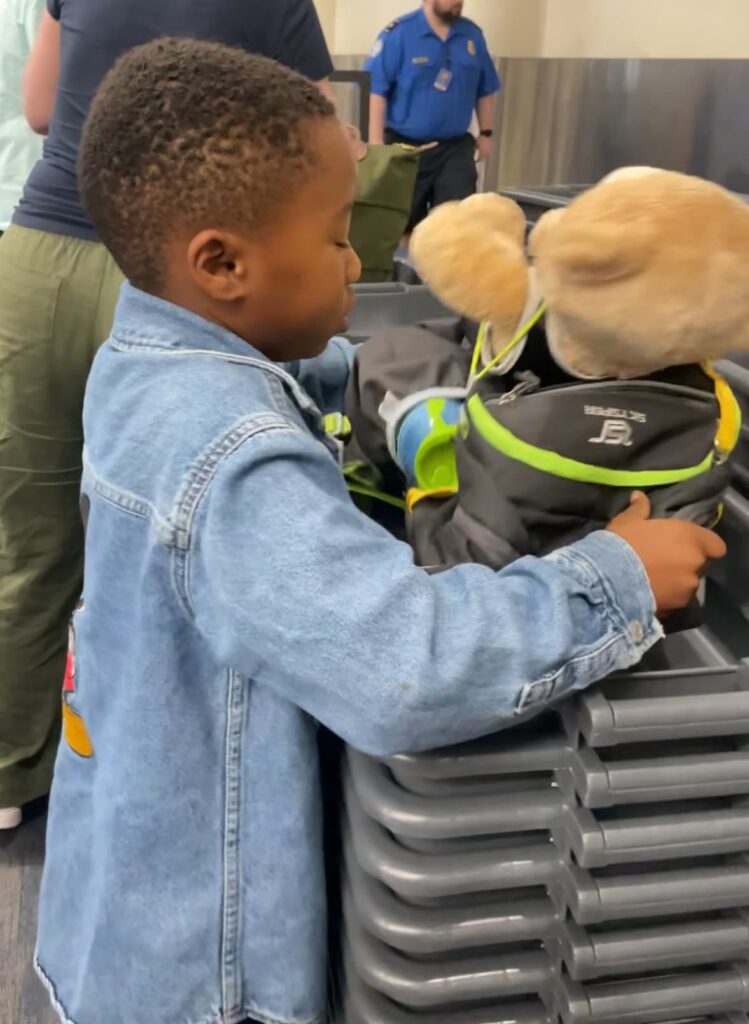 Kindergartener putting his stuff in the tote at TSA airport security