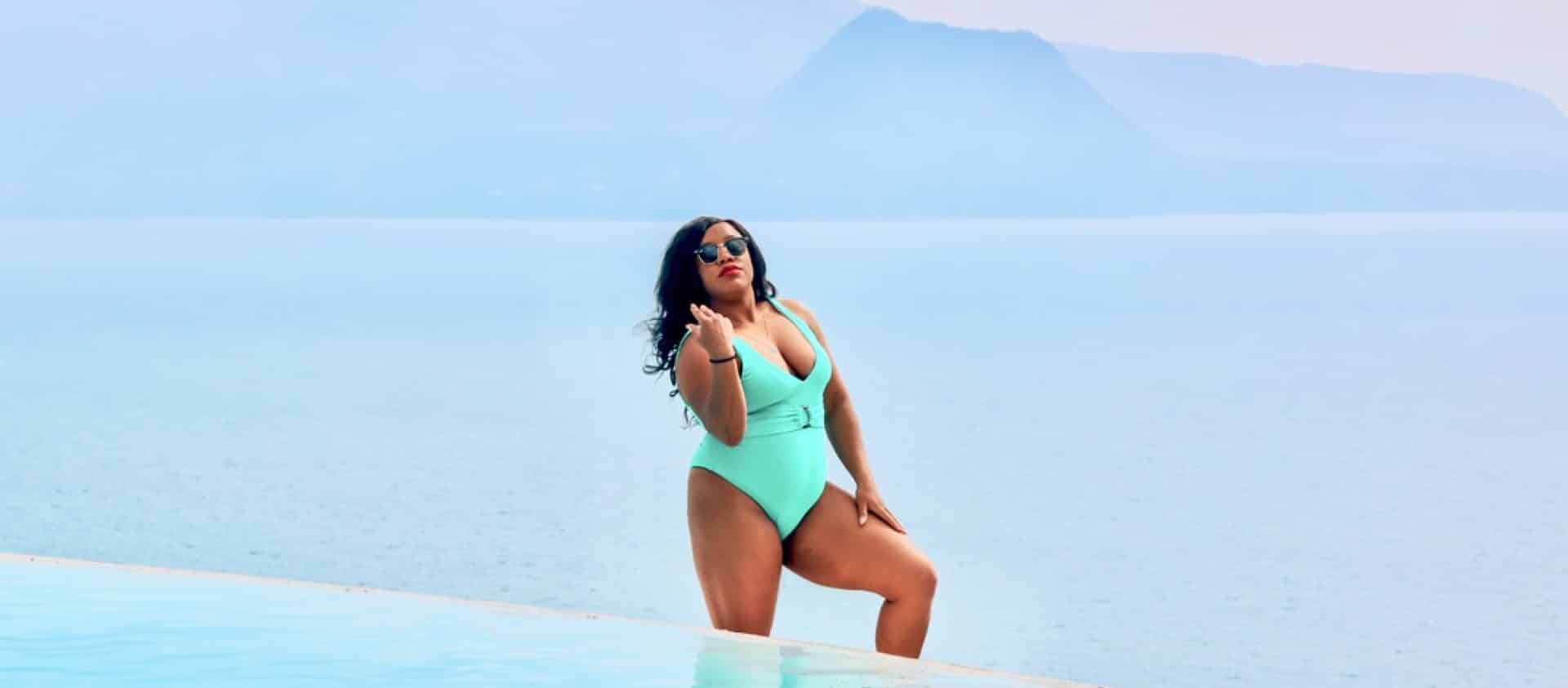 women in green swimsuit standing behind the pool with the volcanoes in the back in Antigua, Guatemala