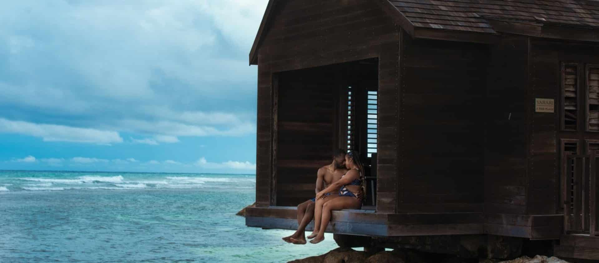 Couple sitting on the dock of the overwater massage hut in Jamaica