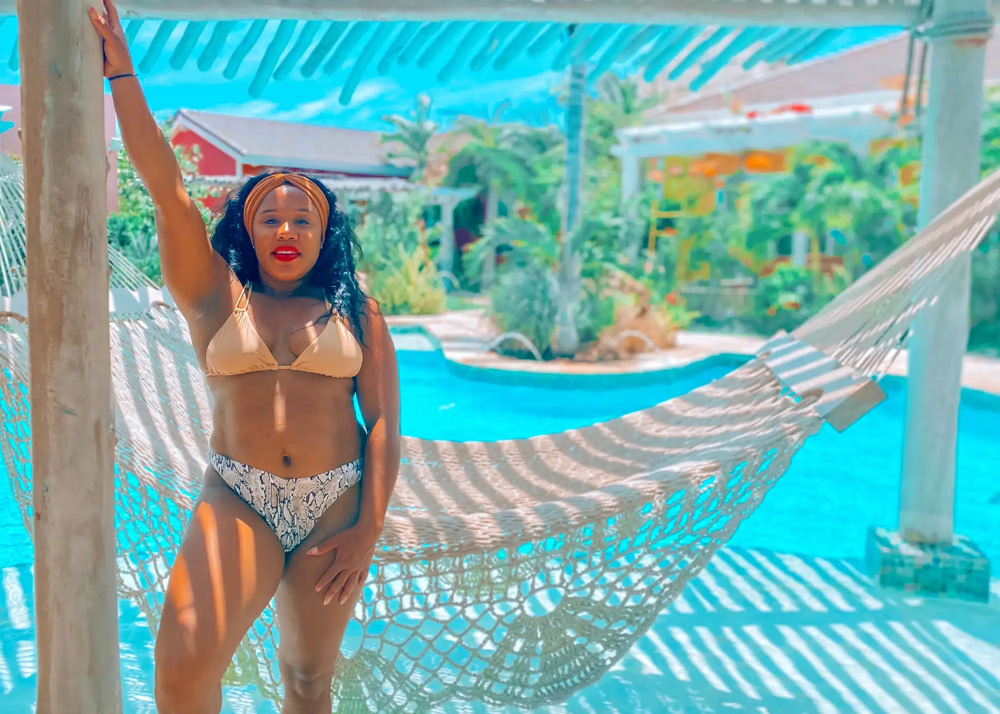 Marquita stands beside a woven hammock suspended over a crystal-clear pool at Boardwalk Boutique Hotel in Aruba.