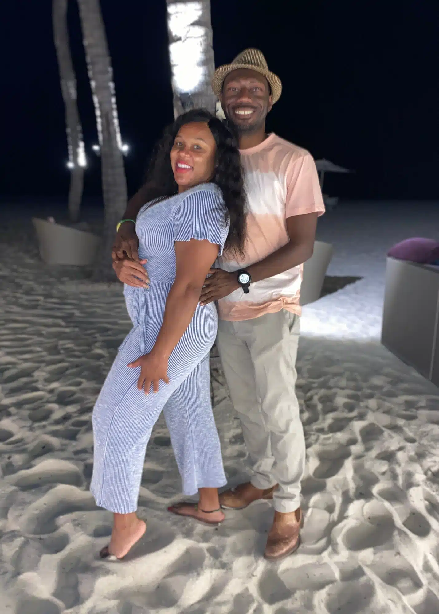 Marquita and her husband smile and pose together on the sand at night beneath glowing palm trees at Bucuti Hotel on Eagle Beach. The romantic beachfront setting adds to the appeal of where to stay in Aruba for couples seeking a peaceful, luxury escape.