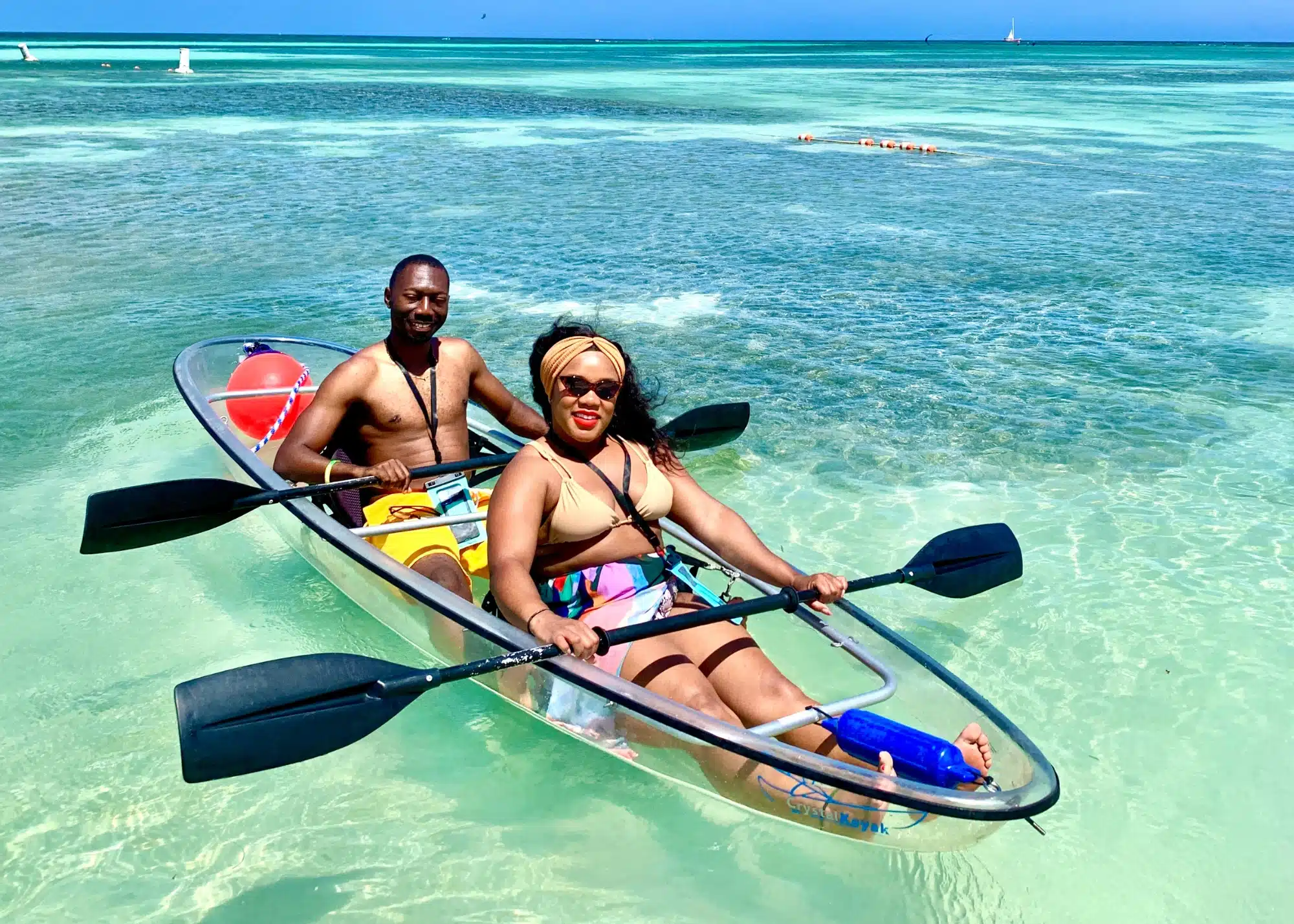 Marquita and her husband kayaking in a clear-bottom boat over turquoise waters in Aruba. The shallow sea and vibrant blue hues highlight why this island is home to some of the best beaches in Aruba.