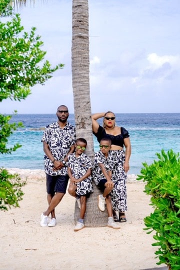 Mom and dad, with twin boys, posing on a palm tree in front of the ocean