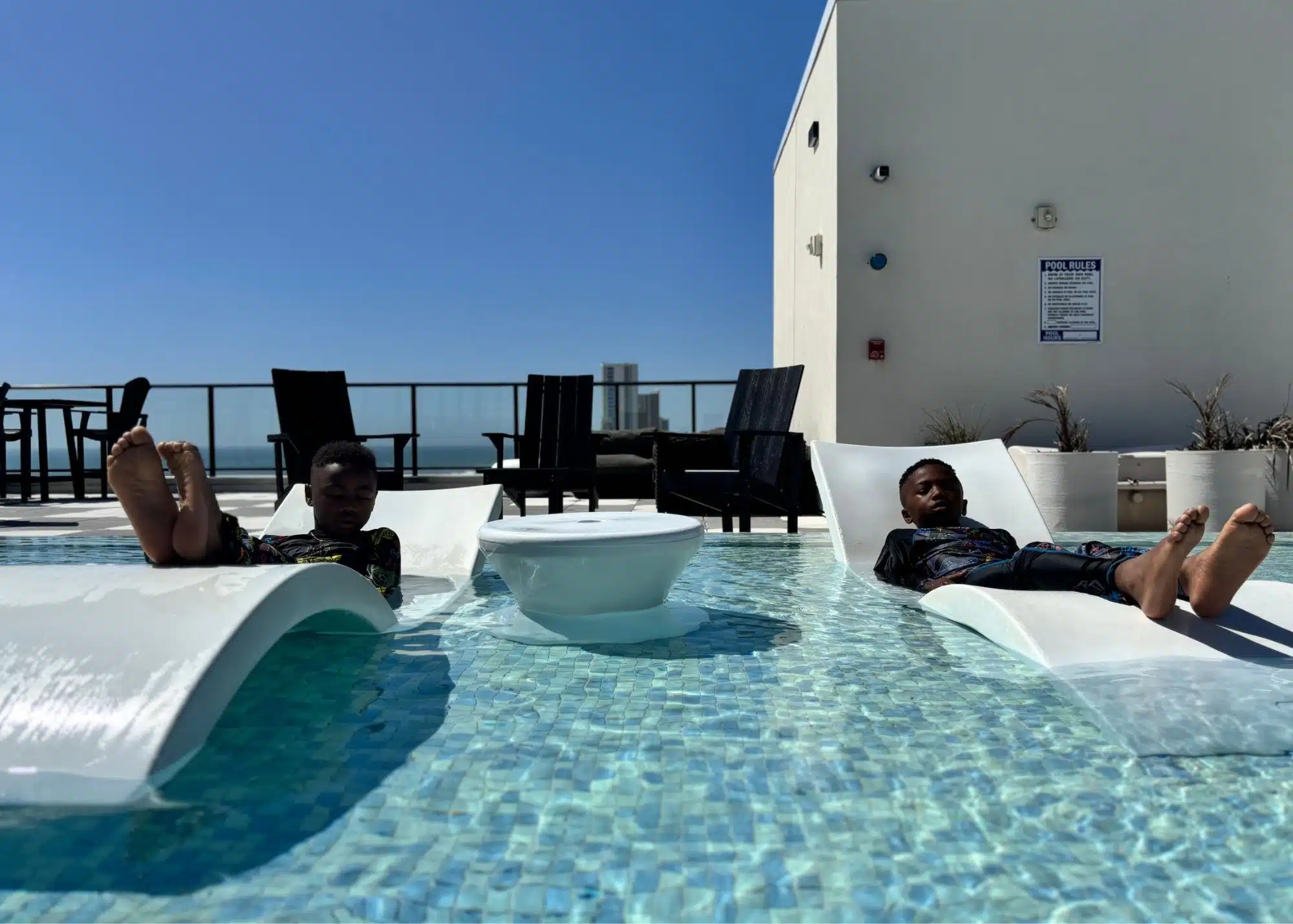 Marquita’s sons relax on partially submerged lounge chairs in the rooftop pool at the family’s beachfront vacation rental in Gulf Shores Alabama.