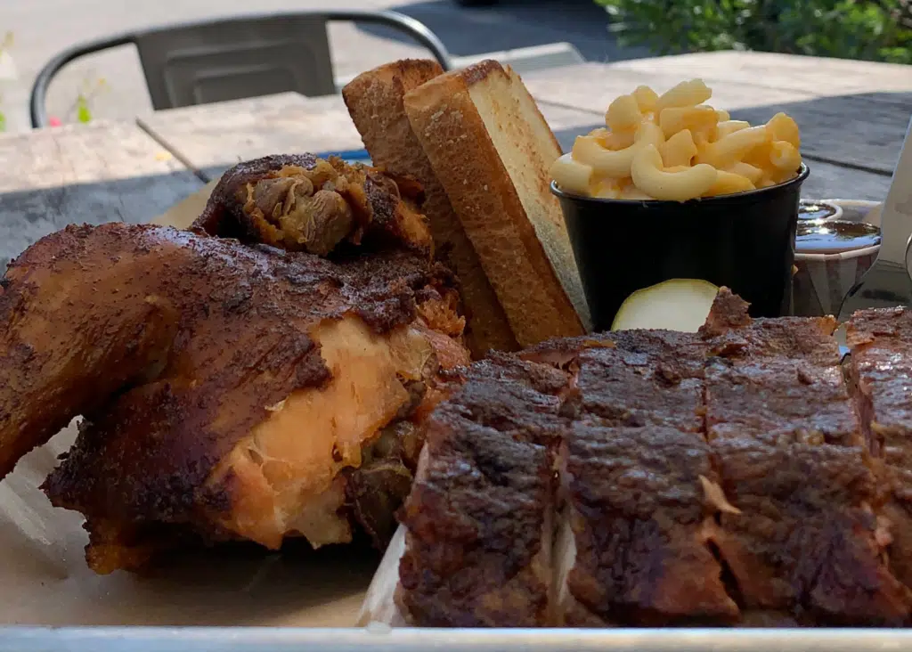 Smoked chicken and sliced barbecue meat fill a tray at Hog Wild Beach and BBQ with thick slices of toasted bread and creamy macaroni and cheese on the side.